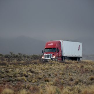 An image of a dry van on a desert road. Used to represent our standard ground, Turckload, Less-Than-Truckload training.